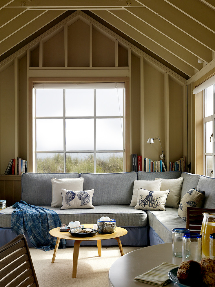 На фото: гостиная комната в морском стиле с бежевыми стенами и синим диваном