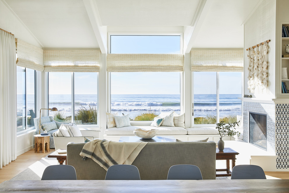 На фото: гостиная комната:: освещение в морском стиле с белыми стенами, светлым паркетным полом, стандартным камином, фасадом камина из плитки и бежевым полом