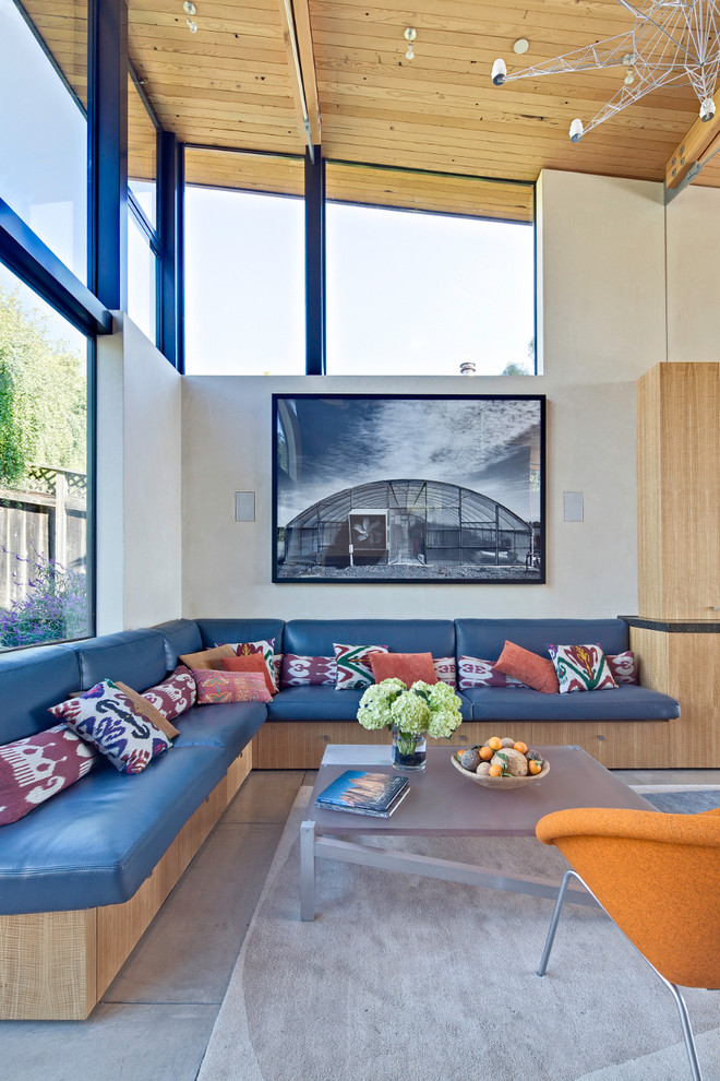 Large beach style concrete floor living room photo in San Francisco with white walls, a standard fireplace, a stone fireplace and a wall-mounted tv