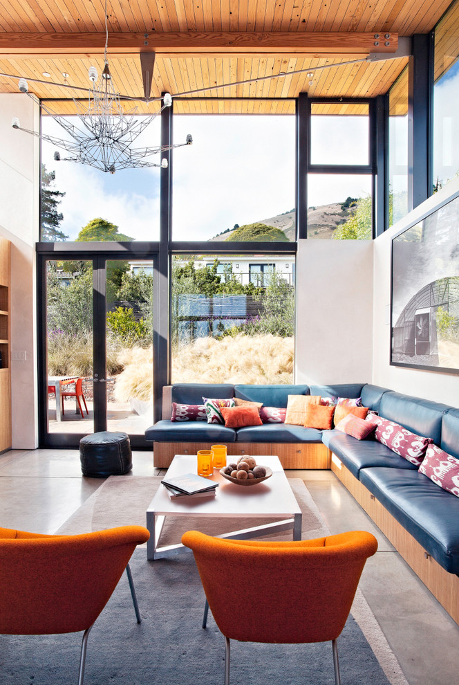 Living room - large coastal concrete floor living room idea in San Francisco with white walls and a wall-mounted tv