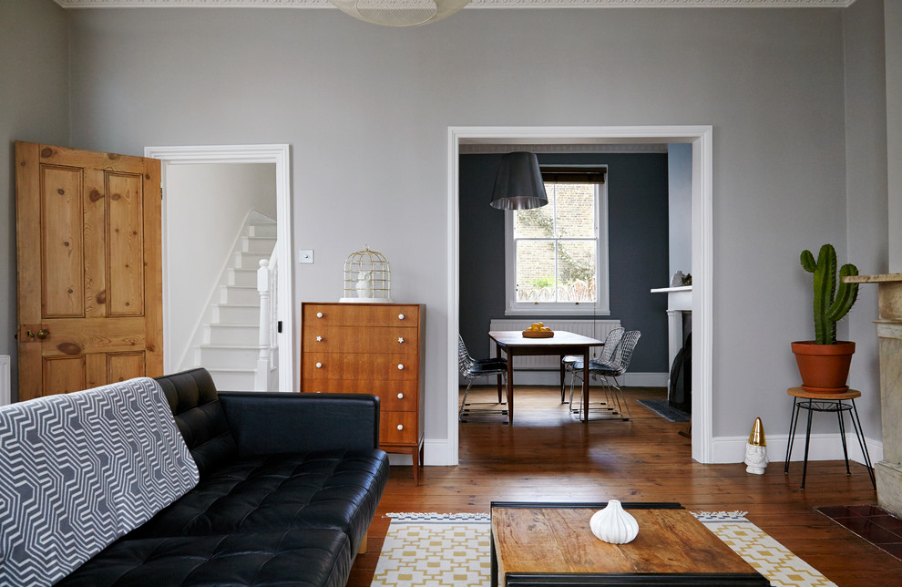 Idée de décoration pour un salon vintage avec un mur gris et un sol en bois brun.