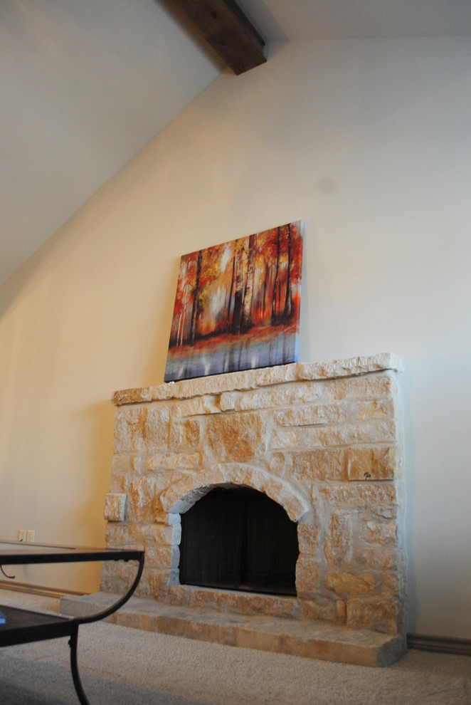 На фото: открытая гостиная комната среднего размера с бежевыми стенами, ковровым покрытием, стандартным камином, фасадом камина из камня и телевизором на стене с