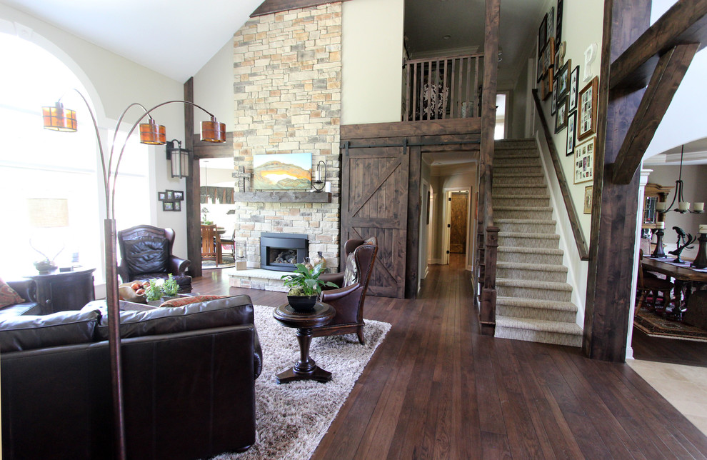 Inspiration for a large rustic formal mezzanine living room in Cleveland with beige walls, dark hardwood flooring, a standard fireplace, a stone fireplace surround and brown floors.