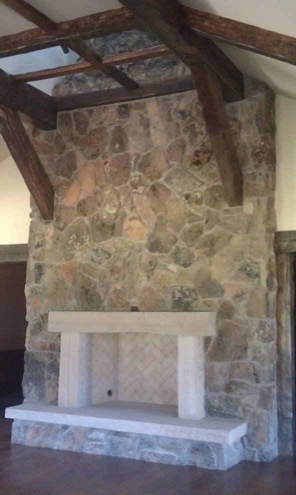На фото: гостиная комната в классическом стиле с бежевыми стенами, темным паркетным полом, стандартным камином и фасадом камина из камня