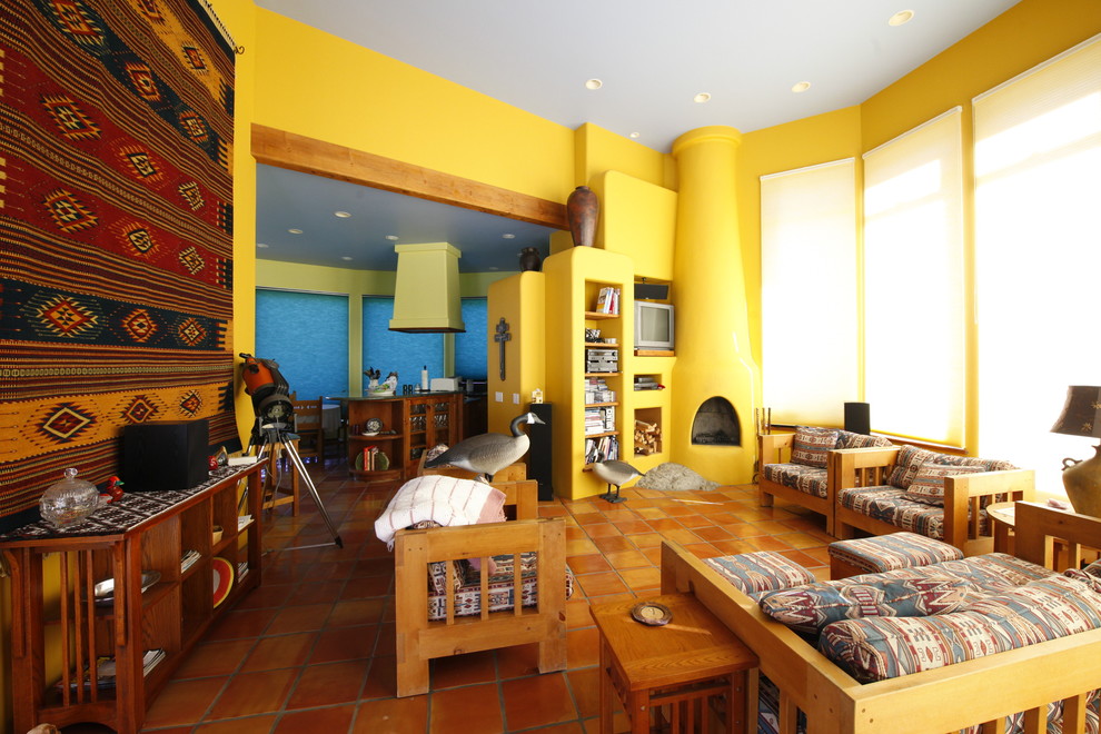Immagine di un soggiorno contemporaneo aperto con sala formale, pareti gialle, pavimento in terracotta, parete attrezzata, camino ad angolo e cornice del camino in cemento