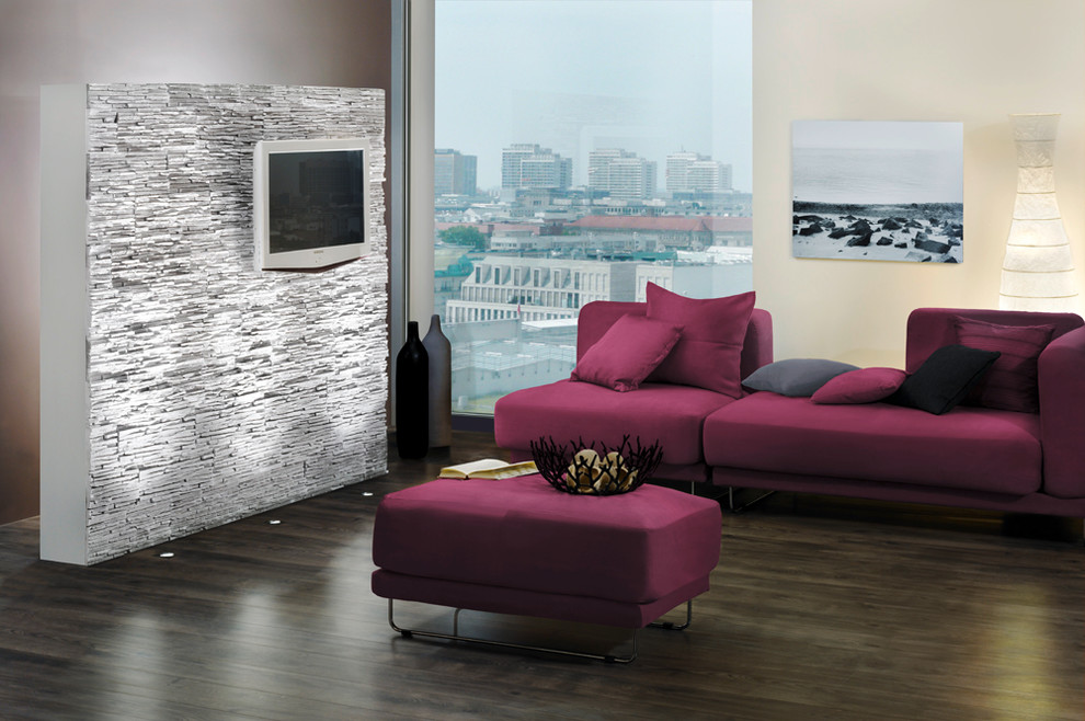 Modelo de salón para visitas abierto moderno pequeño con paredes grises, televisor colgado en la pared, suelo de madera oscura y marco de chimenea de yeso