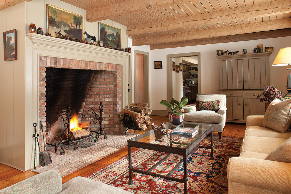 Ejemplo de salón de estilo de casa de campo con paredes blancas, suelo de madera en tonos medios, todas las chimeneas y marco de chimenea de ladrillo