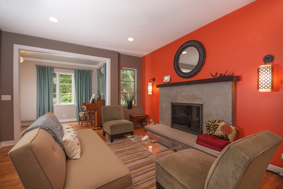 Пример оригинального дизайна: гостиная комната среднего размера в современном стиле с оранжевыми стенами, стандартным камином и акцентной стеной