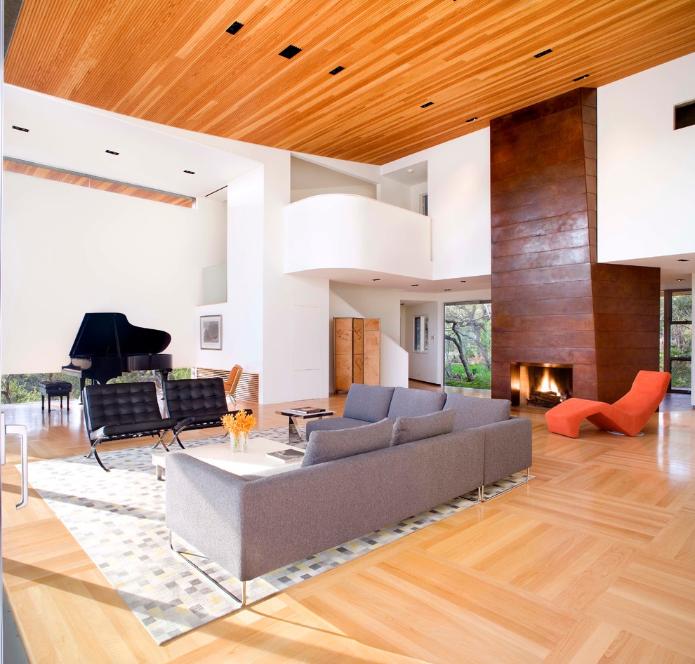 Пример оригинального дизайна: открытая гостиная комната в современном стиле с белыми стенами, светлым паркетным полом, стандартным камином и фасадом камина из металла без телевизора