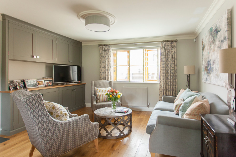 Esempio di un piccolo soggiorno design chiuso con pareti grigie, pavimento in legno massello medio, TV autoportante e pavimento marrone