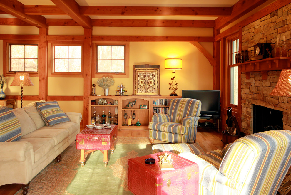 Esempio di un soggiorno american style di medie dimensioni e aperto con pareti gialle, pavimento in legno massello medio, camino classico e cornice del camino in pietra