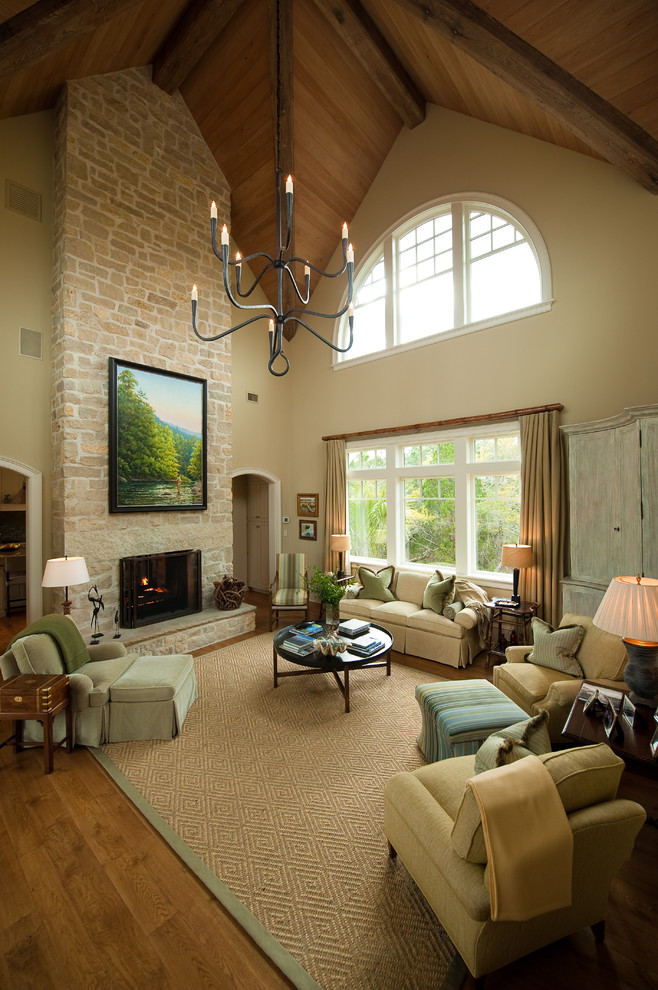 Пример оригинального дизайна: большая гостиная комната в классическом стиле с бежевыми стенами, паркетным полом среднего тона, стандартным камином, фасадом камина из камня и красивыми шторами без телевизора