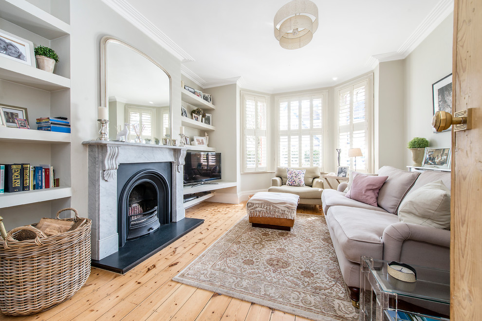 Mittelgroßes, Abgetrenntes Klassisches Wohnzimmer mit beiger Wandfarbe, braunem Holzboden, Kamin, freistehendem TV und Kaminumrandung aus Stein in London