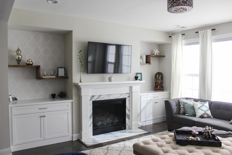 На фото: открытая гостиная комната среднего размера в стиле неоклассика (современная классика) с серыми стенами, темным паркетным полом, стандартным камином, фасадом камина из камня и телевизором на стене с