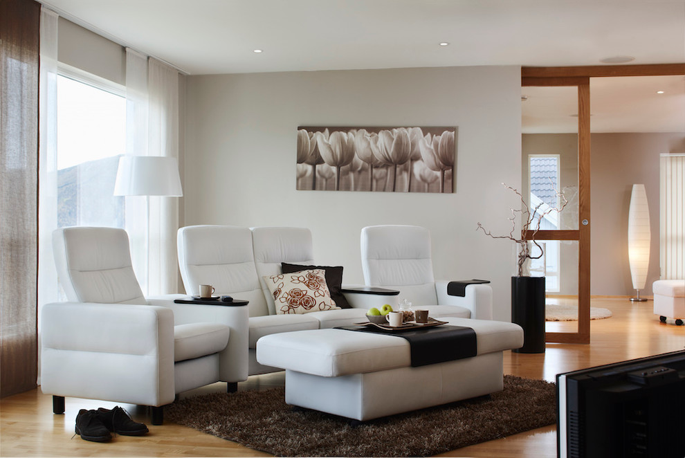 На фото: гостиная комната в стиле модернизм с белыми стенами и светлым паркетным полом с