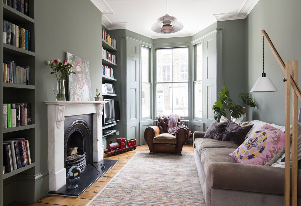 This is an example of a traditional living room in London with green walls, medium hardwood flooring, a standard fireplace and brown floors.
