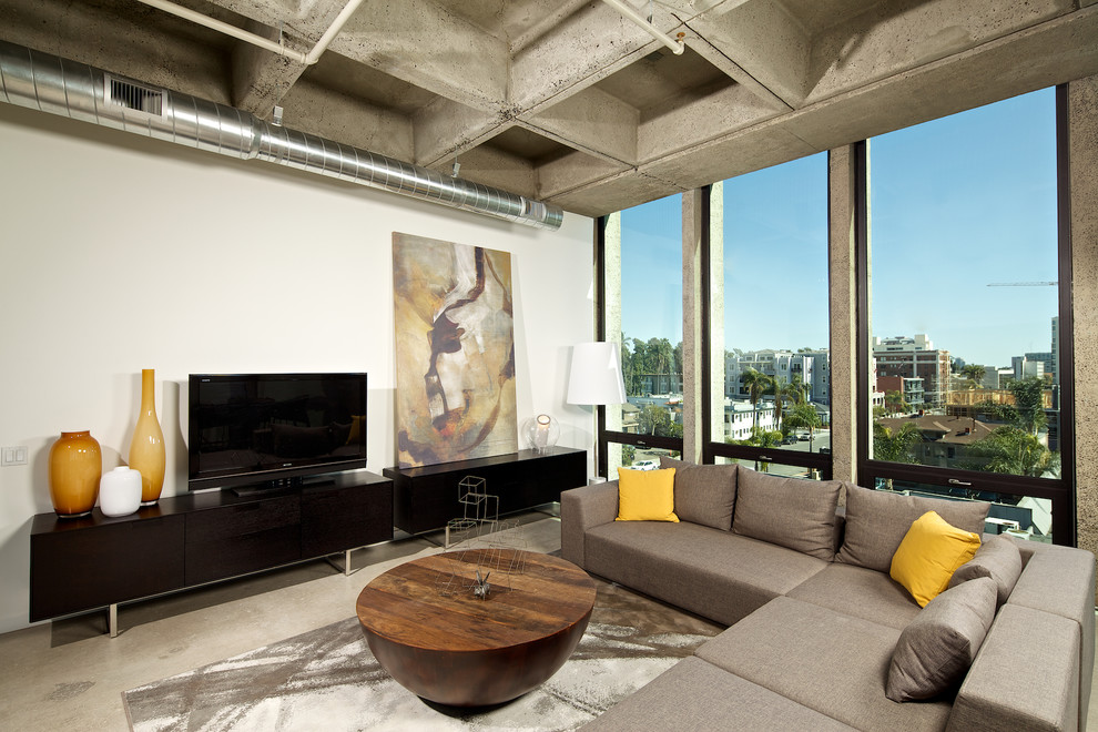 Repräsentatives Industrial Wohnzimmer ohne Kamin mit weißer Wandfarbe, Betonboden und freistehendem TV in San Diego