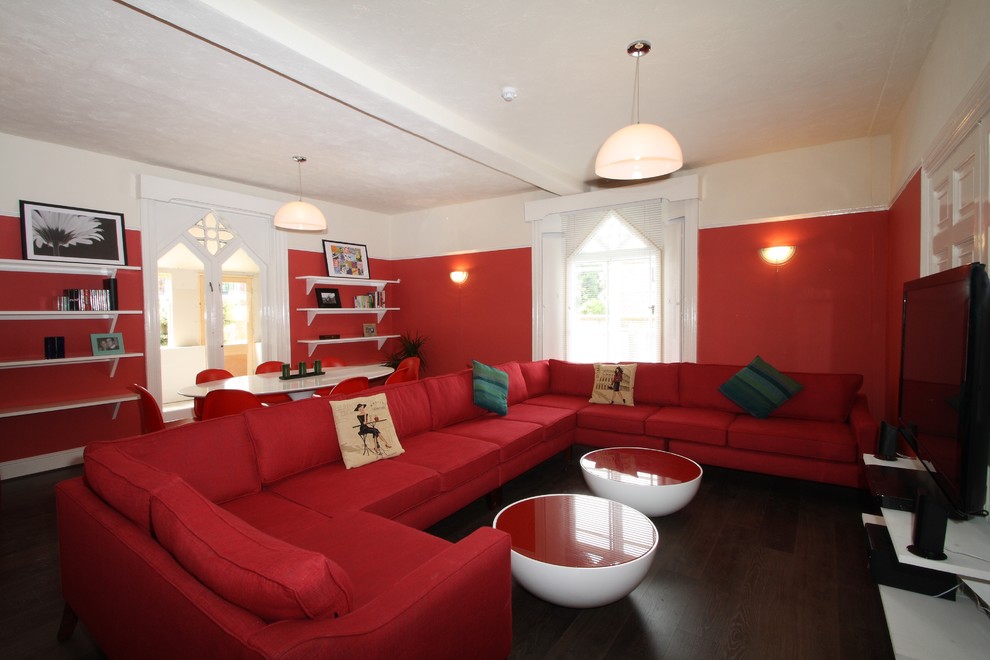 Large bohemian formal open plan living room in London with red walls, no fireplace and a freestanding tv.