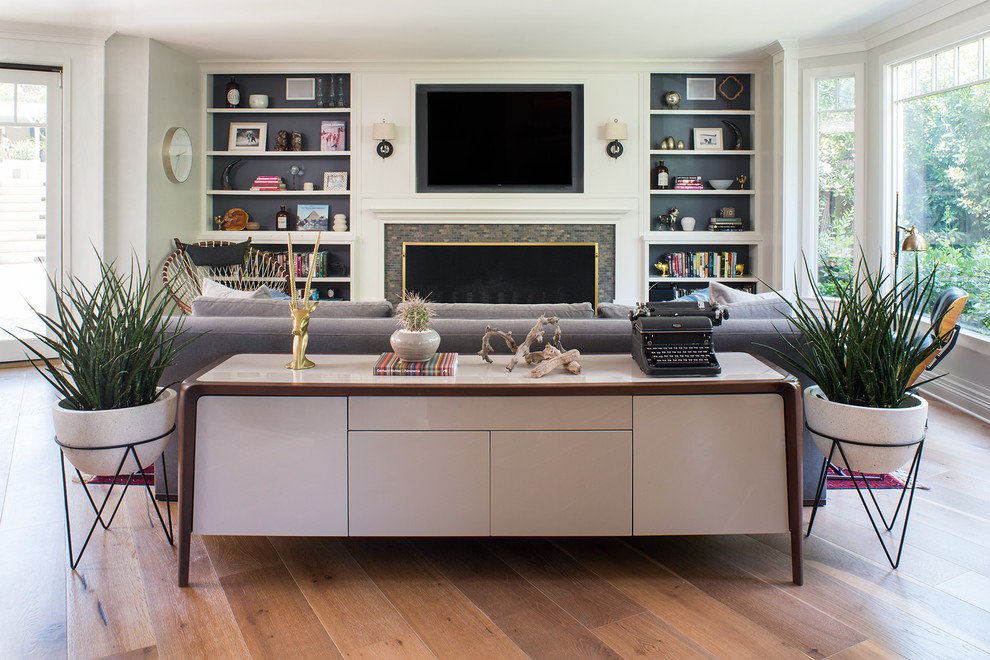 Inspiration for a mid-sized eclectic open concept light wood floor and brown floor living room remodel in San Francisco with white walls, a standard fireplace, a tile fireplace and a wall-mounted tv