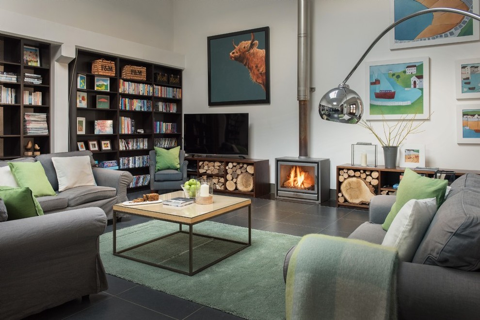 サセックスにあるエクレクティックスタイルのおしゃれなリビング (白い壁、薪ストーブ、金属の暖炉まわり、据え置き型テレビ、グレーの床) の写真