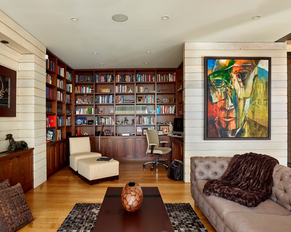 Immagine di un soggiorno minimal aperto con libreria, pavimento in legno massello medio e tappeto