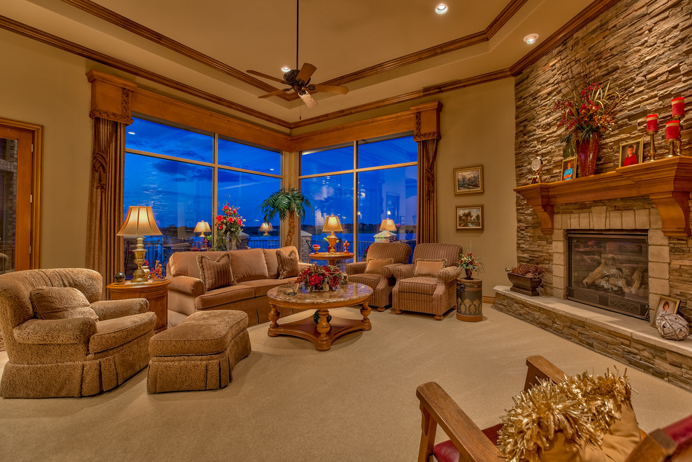 This is an example of a large classic formal open plan living room in Omaha with brown walls, carpet, a stone fireplace surround, a standard fireplace, a freestanding tv and beige floors.