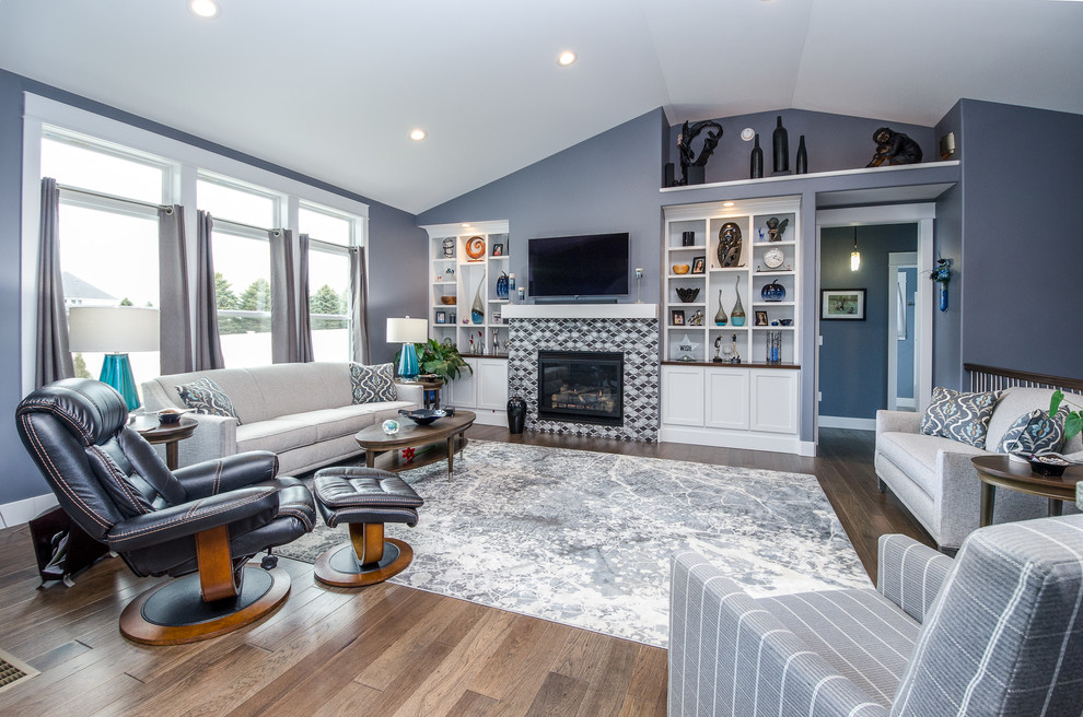 Klassisches Wohnzimmer mit blauer Wandfarbe, braunem Holzboden, Kamin, gefliester Kaminumrandung, TV-Wand und braunem Boden in Sonstige