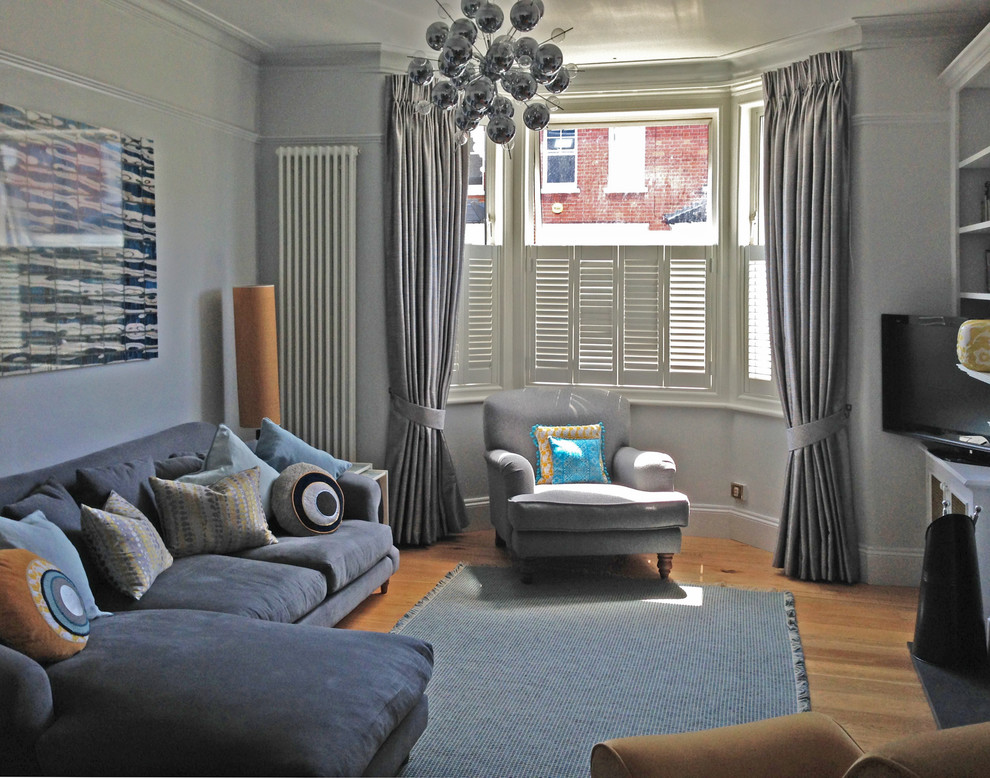 Mittelgroßes, Abgetrenntes Modernes Wohnzimmer mit grauer Wandfarbe, hellem Holzboden, Kamin, Kaminumrandung aus Stein und freistehendem TV in Berkshire
