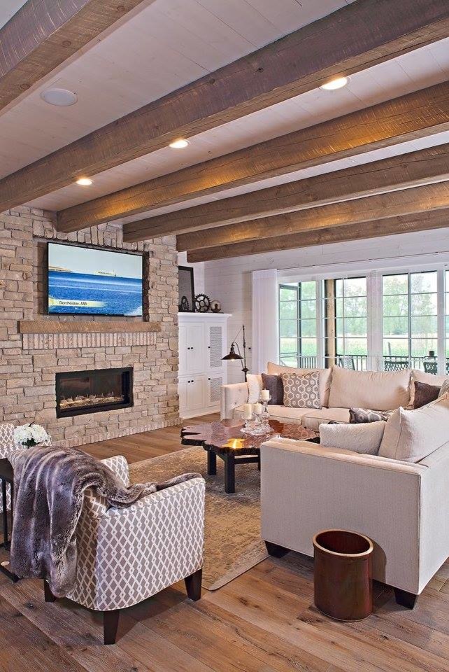 Imagen de salón abierto rústico de tamaño medio con paredes blancas, suelo de madera clara, chimenea lineal, marco de chimenea de piedra y televisor colgado en la pared