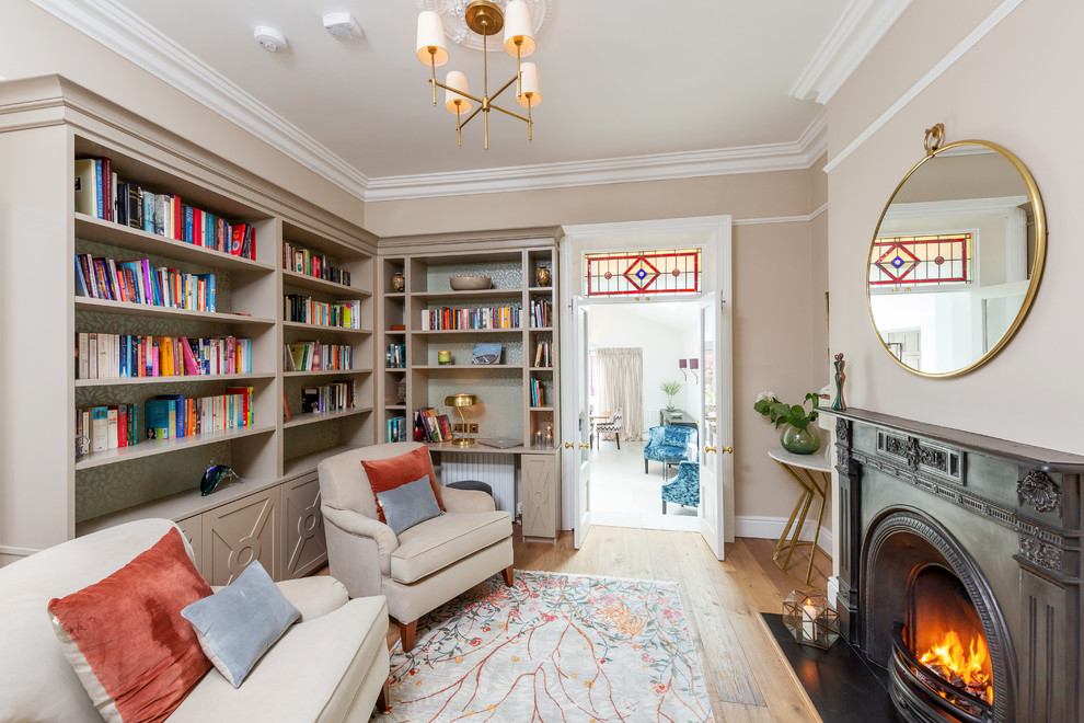На фото: гостиная комната в классическом стиле с с книжными шкафами и полками, бежевыми стенами, светлым паркетным полом, стандартным камином и бежевым полом