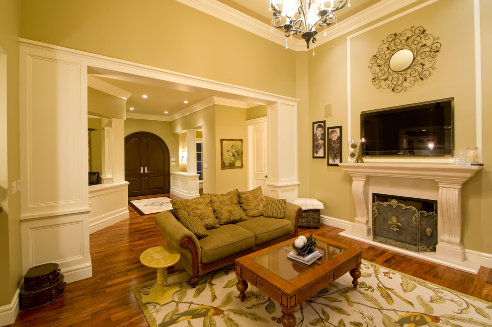 Пример оригинального дизайна: большая парадная, открытая гостиная комната в классическом стиле с бежевыми стенами, паркетным полом среднего тона, стандартным камином, фасадом камина из дерева и телевизором на стене