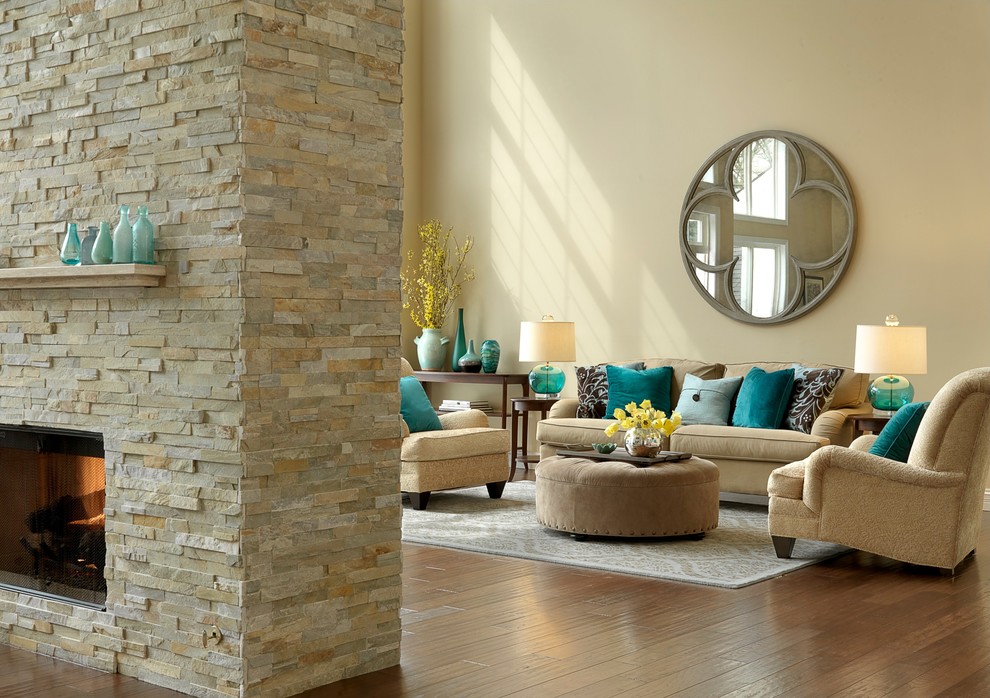 Inspiration pour un grand salon traditionnel ouvert avec un mur beige, un sol en bois brun, une salle de réception, une cheminée double-face, un manteau de cheminée en pierre et aucun téléviseur.