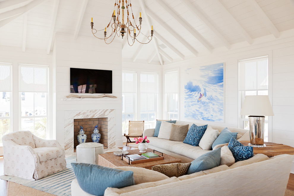 Maritimes Wohnzimmer mit weißer Wandfarbe, braunem Holzboden, Kamin, Kaminumrandung aus Stein und TV-Wand in Charleston