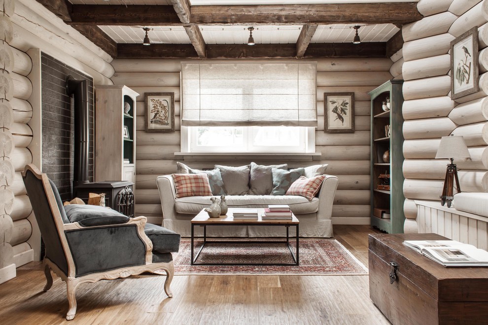 Immagine di un soggiorno country di medie dimensioni e aperto con pareti bianche, pavimento in legno massello medio e stufa a legna