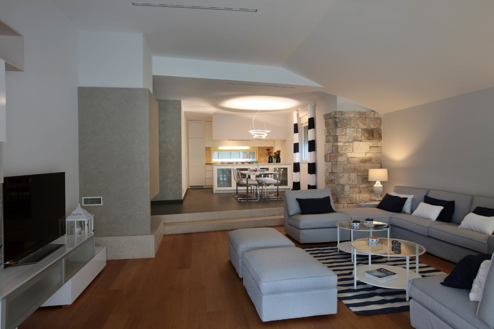 Immagine di un grande soggiorno design aperto con pareti bianche, parquet chiaro, camino bifacciale, TV autoportante e pavimento beige