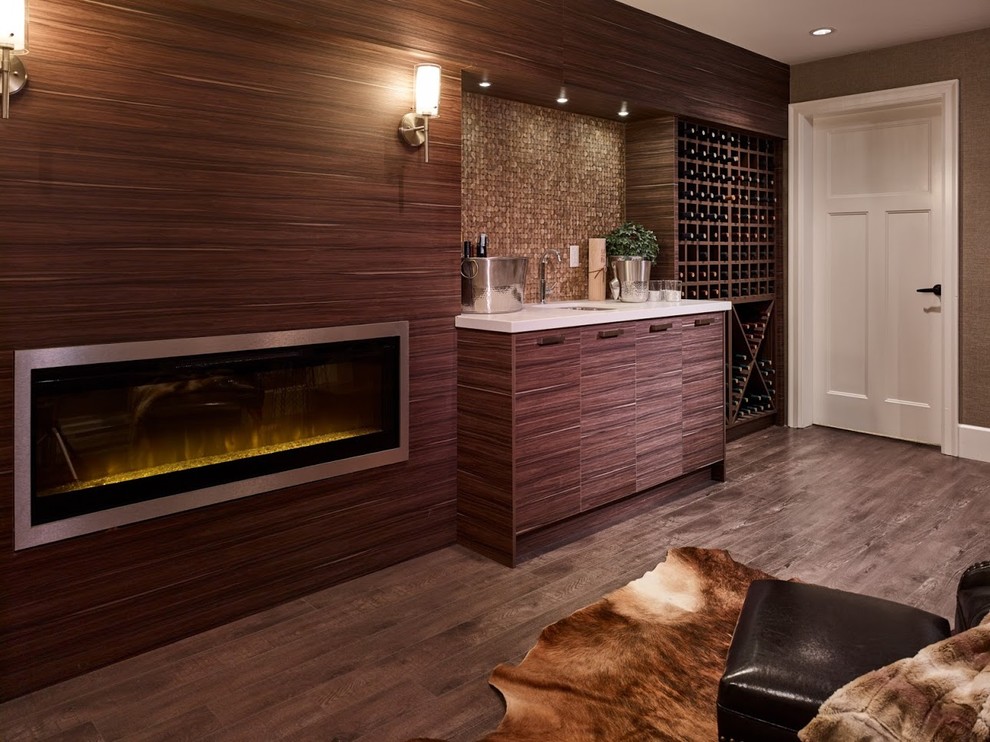 На фото: большая изолированная гостиная комната в стиле модернизм с домашним баром, коричневыми стенами, полом из фанеры, стандартным камином, фасадом камина из дерева и коричневым полом без телевизора
