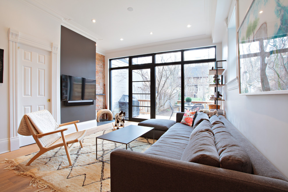 Foto di un soggiorno minimal aperto con pareti bianche, pavimento in legno massello medio, nessun camino, TV a parete e pavimento marrone