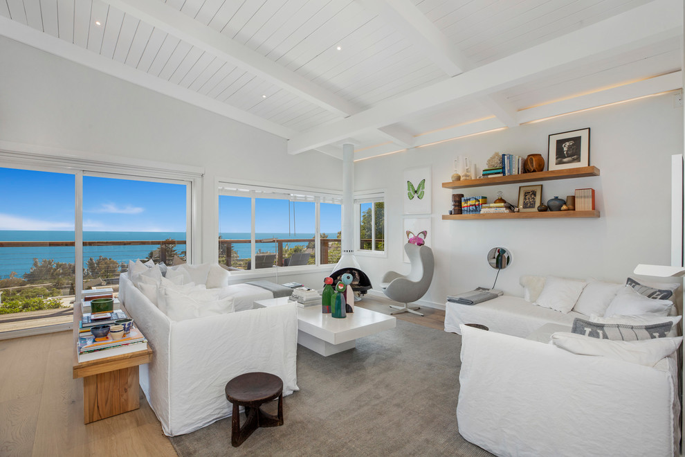 Maritimes Wohnzimmer mit weißer Wandfarbe, braunem Holzboden und braunem Boden in Santa Barbara