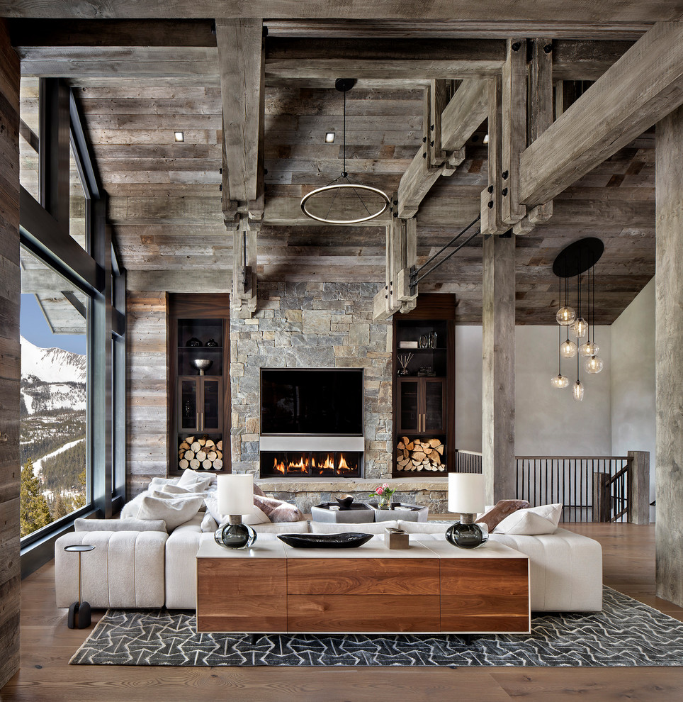 Rustic open plan living room in Other with grey walls, medium hardwood flooring, a ribbon fireplace, a stone fireplace surround, a built-in media unit and brown floors.