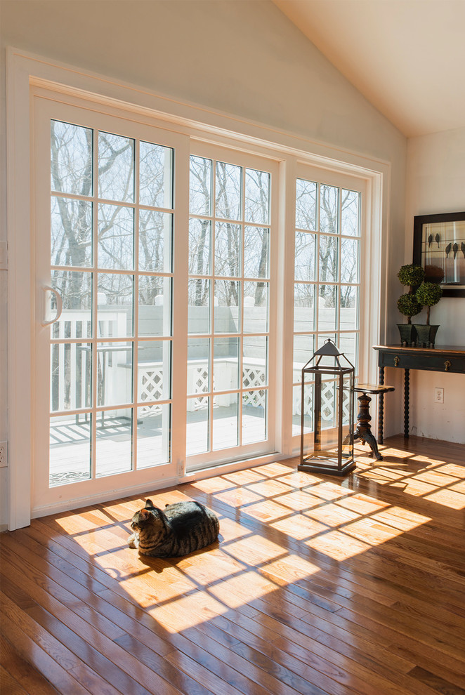 Mittelgroßes, Abgetrenntes Uriges Wohnzimmer mit weißer Wandfarbe, braunem Holzboden und buntem Boden in Bridgeport