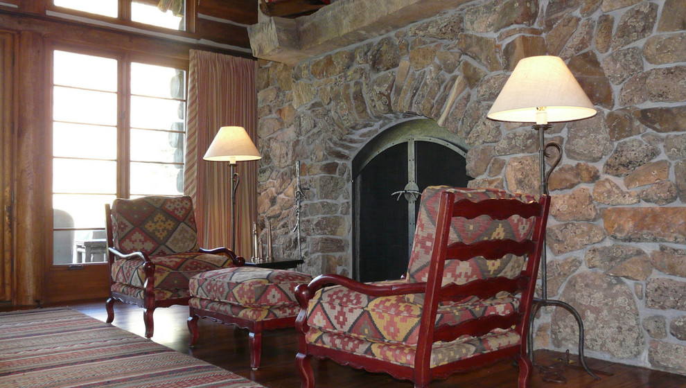 Пример оригинального дизайна: огромная открытая гостиная комната в стиле рустика с коричневыми стенами, темным паркетным полом, стандартным камином и фасадом камина из камня без телевизора