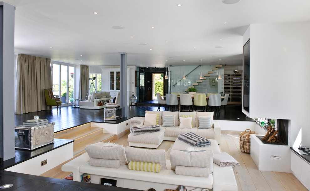 Modernes Wohnzimmer mit weißer Wandfarbe, hellem Holzboden, Tunnelkamin und Multimediawand in London