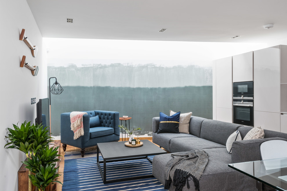 Imagen de salón abierto contemporáneo de tamaño medio sin chimenea con paredes blancas, suelo de madera en tonos medios y televisor independiente