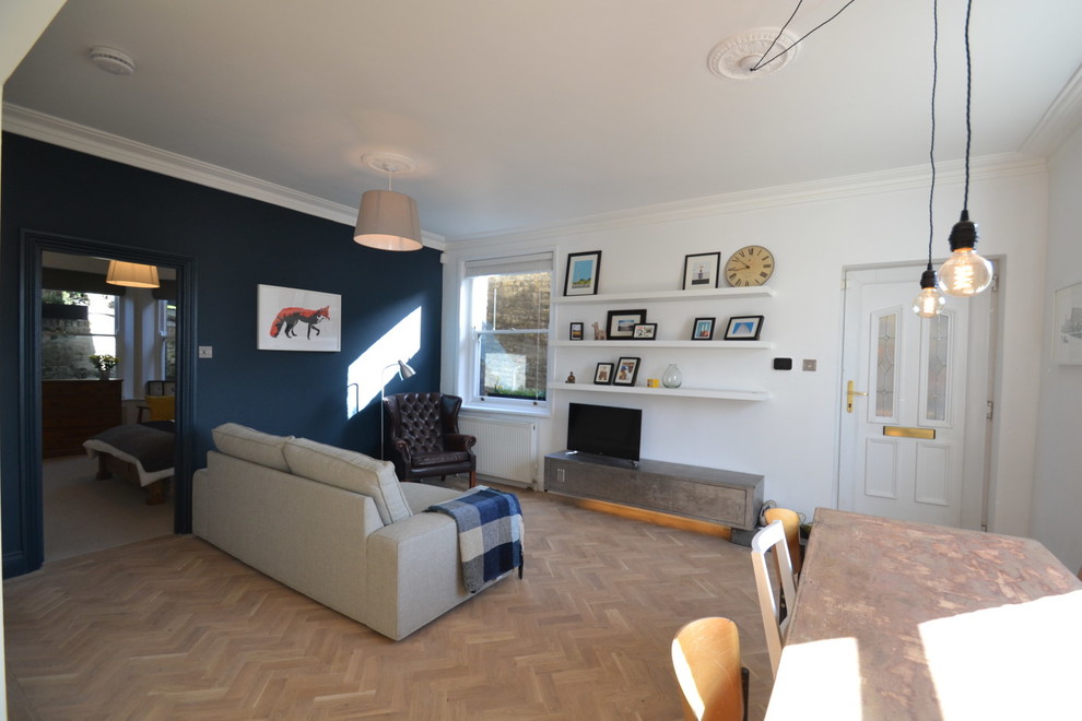 Aménagement d'un salon contemporain avec un mur bleu, parquet clair et un téléviseur encastré.