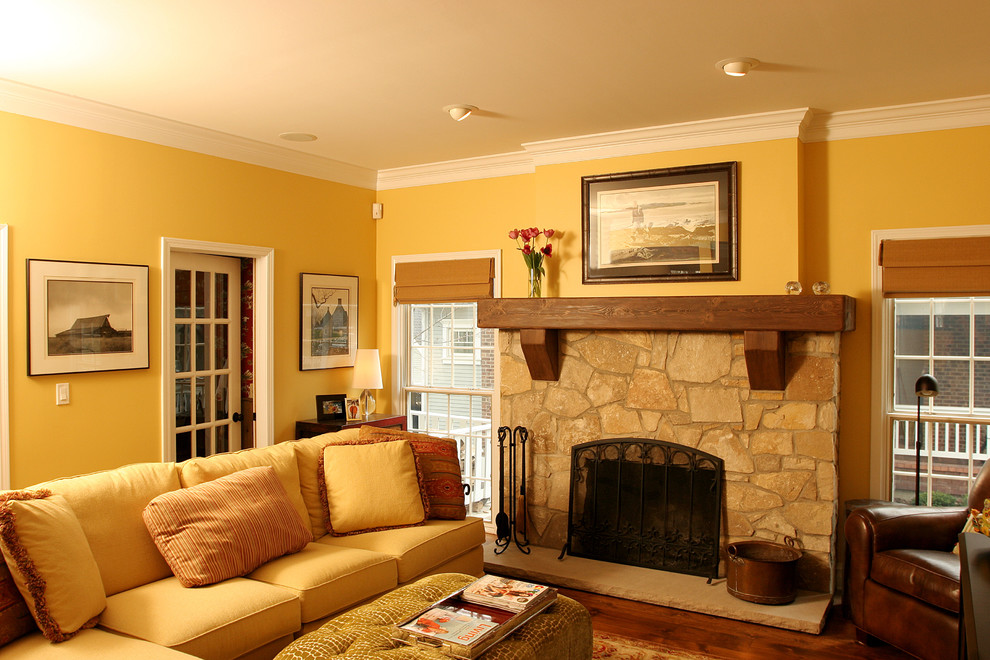 Modelo de salón para visitas cerrado clásico de tamaño medio con paredes amarillas, suelo de madera en tonos medios, todas las chimeneas y marco de chimenea de piedra