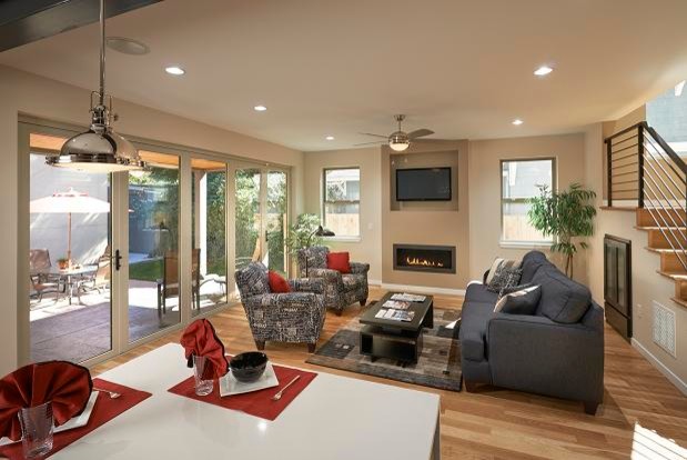 Offenes Modernes Wohnzimmer mit beiger Wandfarbe, hellem Holzboden, Gaskamin, Kaminumrandung aus Metall und TV-Wand in Denver