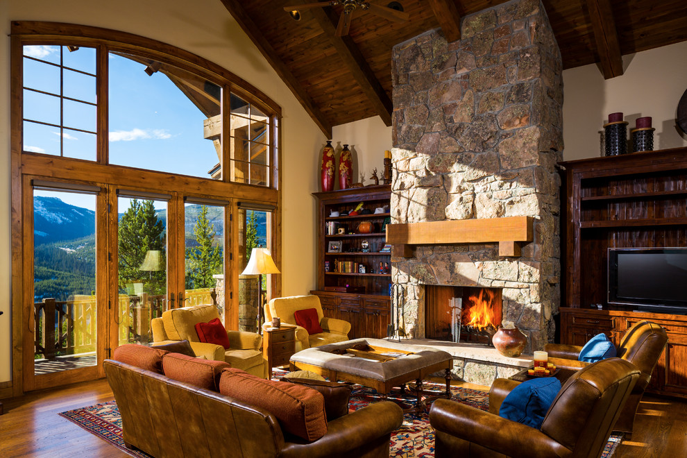 This is an example of a large rustic formal open plan living room in Other with beige walls, medium hardwood flooring, a standard fireplace, a stone fireplace surround and a built-in media unit.