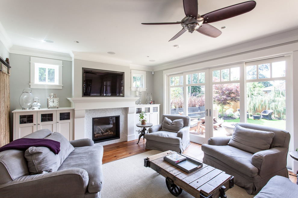Medium sized traditional enclosed living room in Vancouver with grey walls, medium hardwood flooring, a standard fireplace, a tiled fireplace surround and a wall mounted tv.