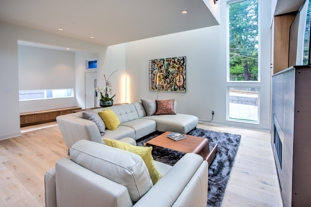 Large contemporary open plan living room in Seattle with white walls, light hardwood flooring, a standard fireplace, a metal fireplace surround and a freestanding tv.