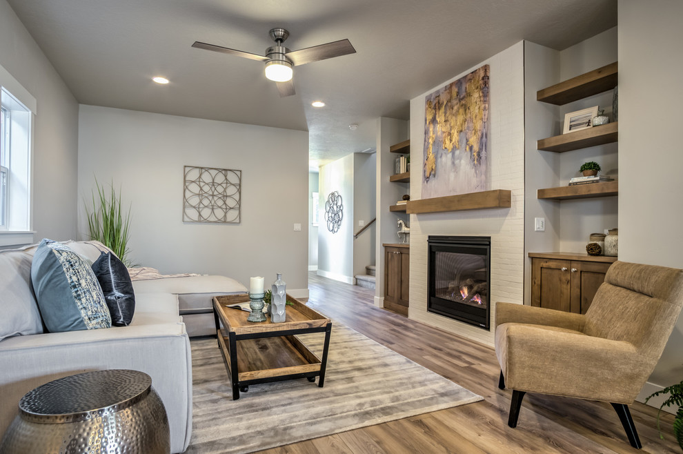 Living room - mid-sized craftsman open concept laminate floor and brown floor living room idea in Boise with gray walls, a standard fireplace, a brick fireplace and a wall-mounted tv